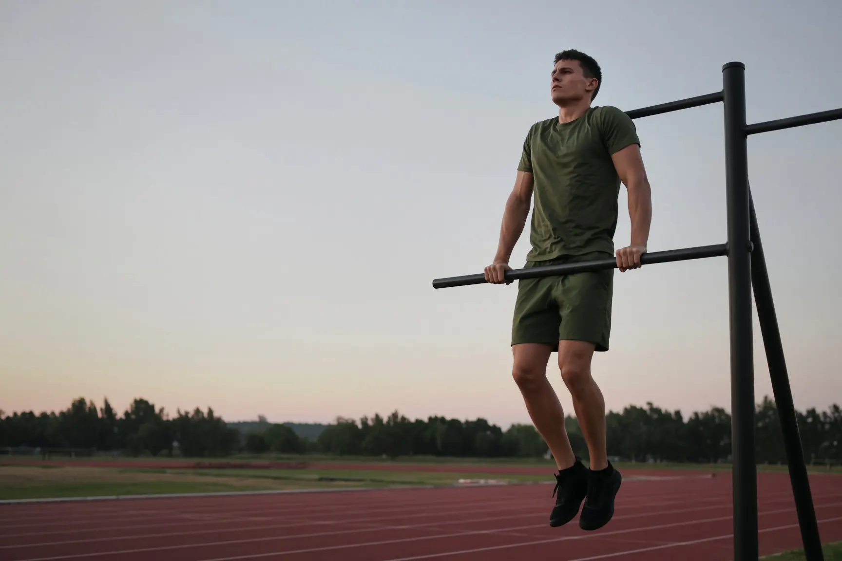 Marine in PT gear on a pull-up bar at dawn